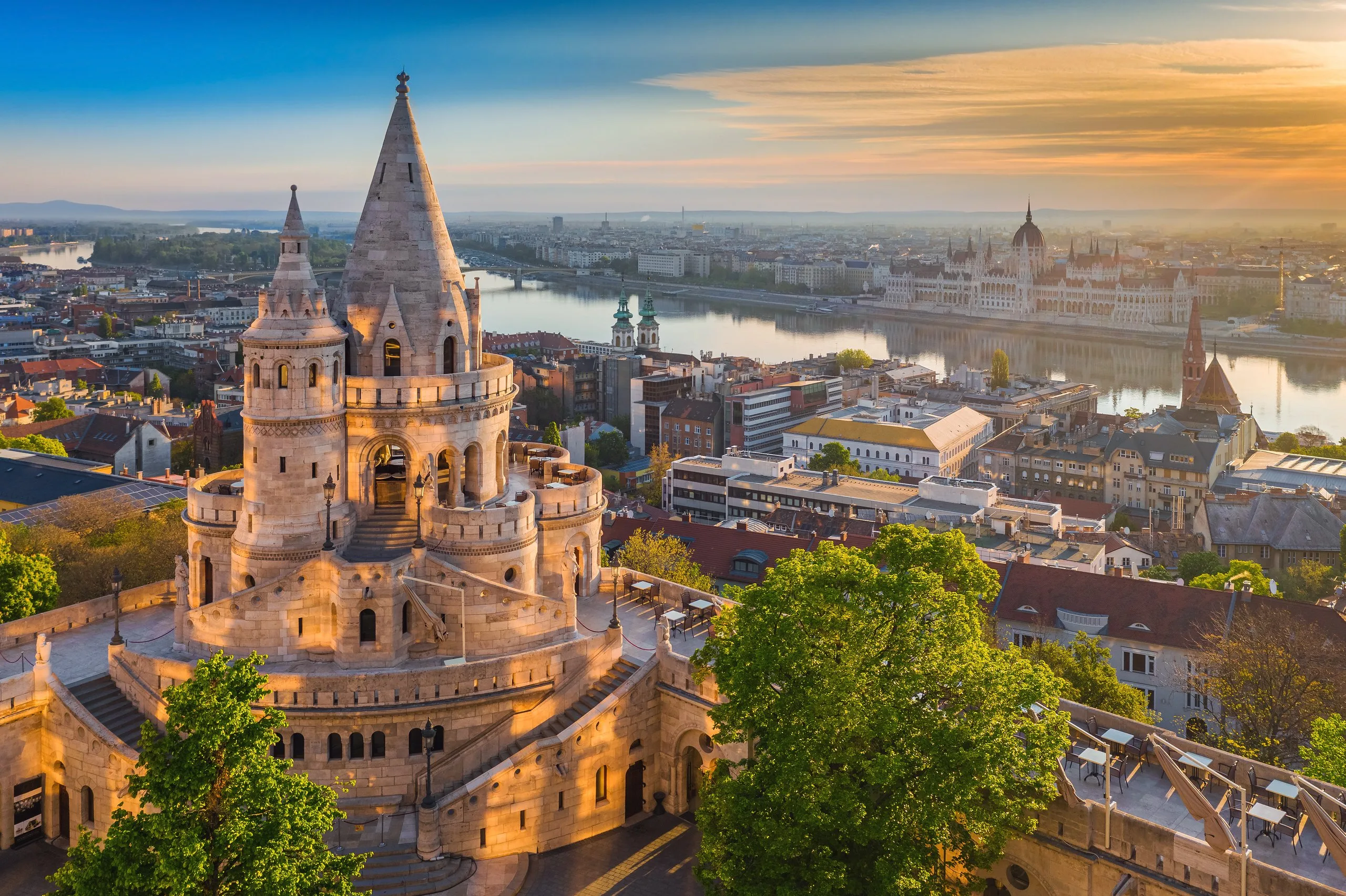Fisherman's Bastion at sunrise, its white stone turrets above the Danube with the Hungarian Parliament on the far bank.