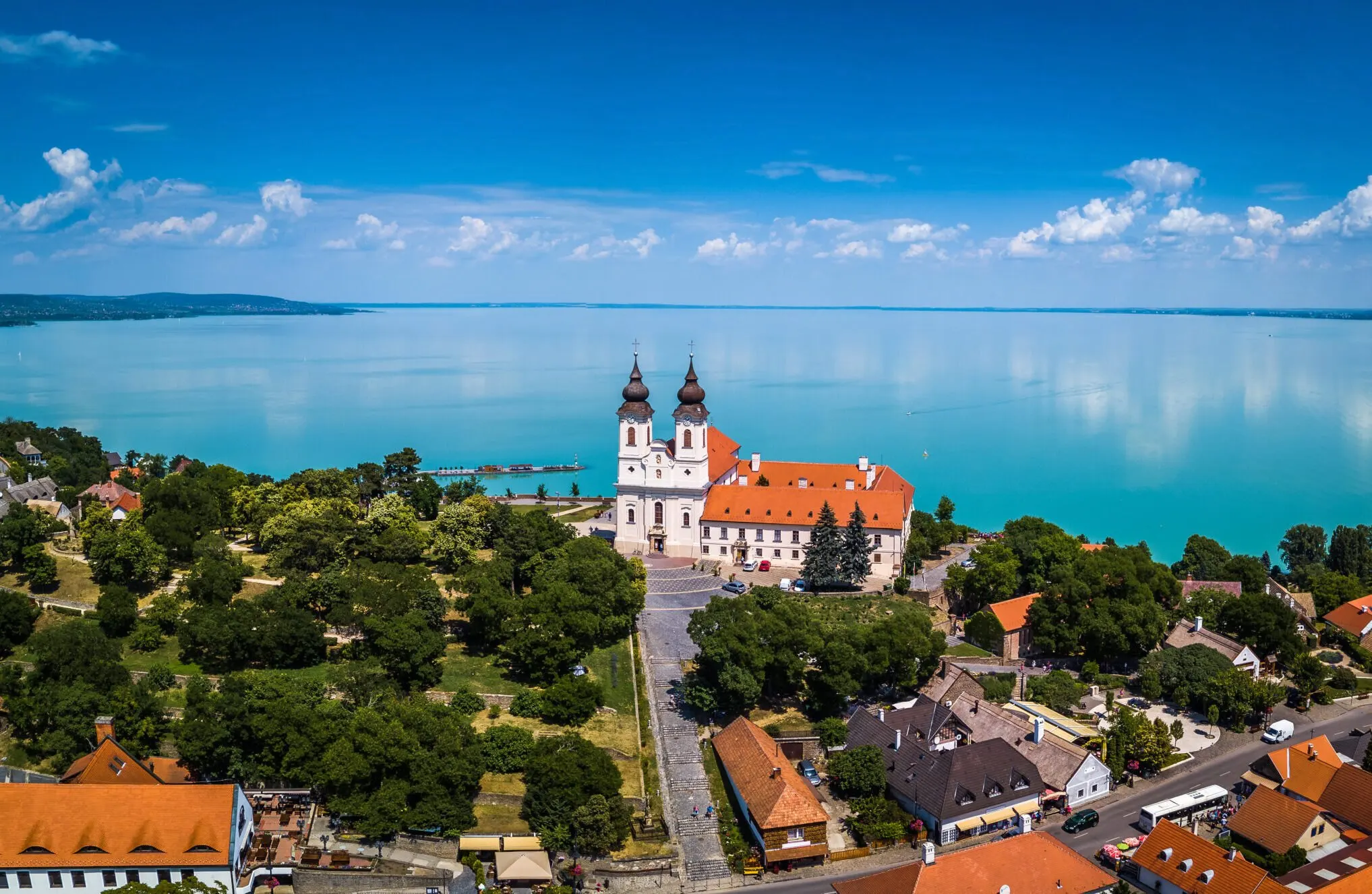 Tihany Abbey's twin towers on the hillside above Lake Balaton, the turquoise water stretching to the horizon.